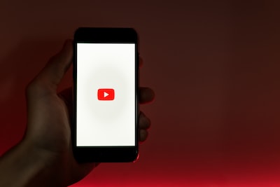 A hand holding a smartphone with the YouTube logo on the screen, symbolizing mobile access to YouTube earnings information for the blog article 'YouTube Revenue Calculator: Calculate Your Earnings Today'